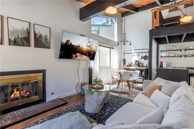 living room with beam ceiling, a towering ceiling, and wood-type flooring