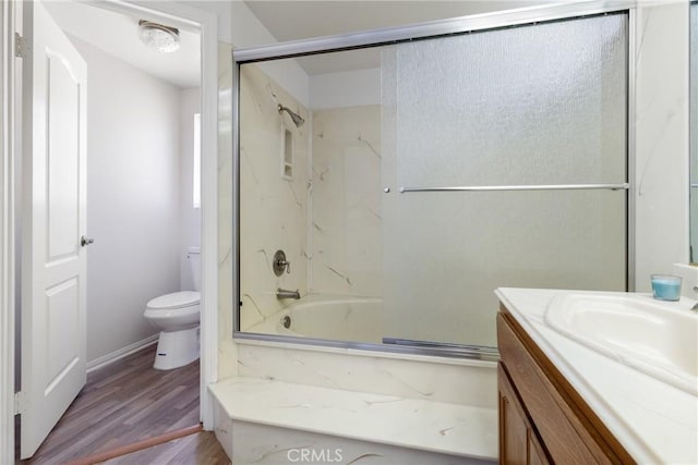 full bathroom featuring hardwood / wood-style floors, vanity, toilet, and shower / bath combination with glass door