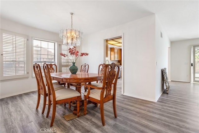 dining room with dark hardwood / wood-style floors and an inviting chandelier