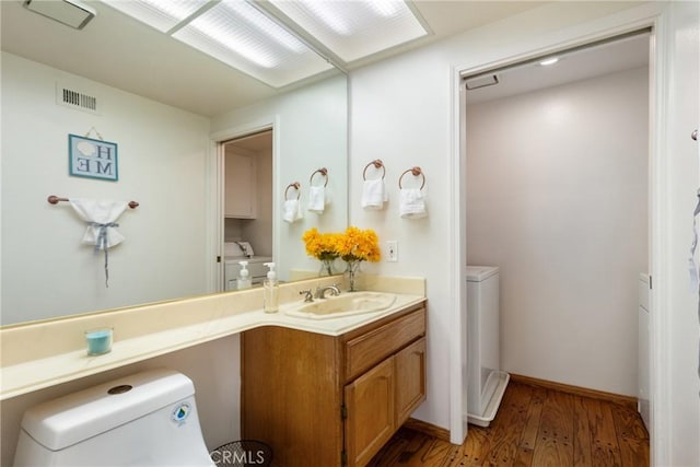 bathroom featuring washer and dryer, vanity, hardwood / wood-style flooring, and toilet