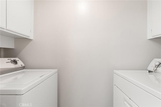 clothes washing area featuring washing machine and dryer and cabinets