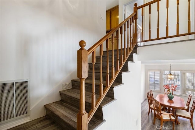 stairs with hardwood / wood-style floors and an inviting chandelier