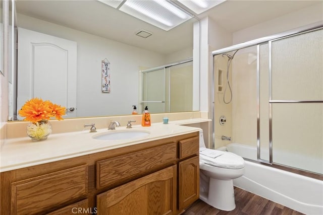 full bathroom featuring combined bath / shower with glass door, vanity, hardwood / wood-style flooring, and toilet