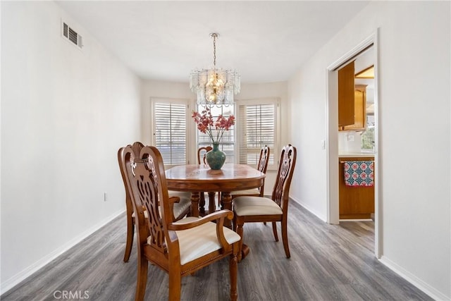 dining room with dark hardwood / wood-style flooring and a notable chandelier