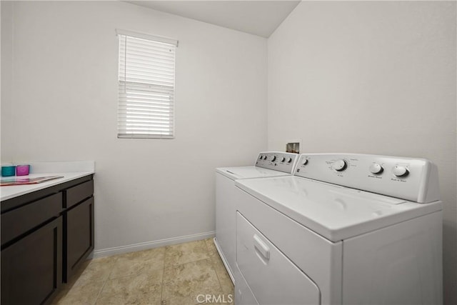 clothes washing area with washer and dryer and cabinets