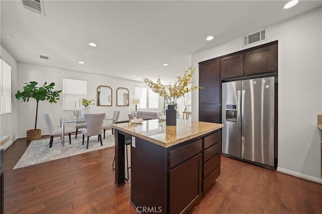 kitchen featuring stainless steel refrigerator with ice dispenser, dark hardwood / wood-style floors, dark brown cabinetry, and a center island