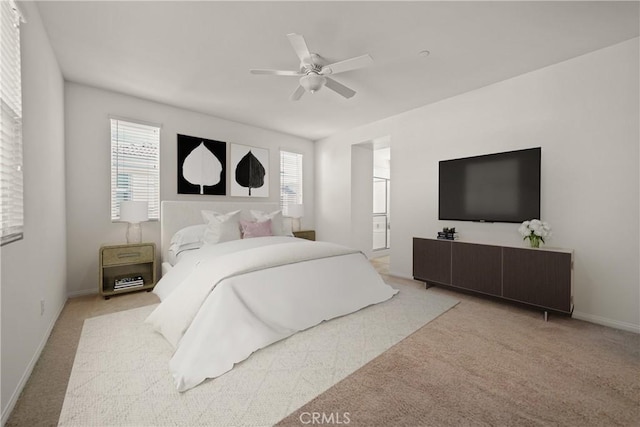 carpeted bedroom featuring ceiling fan, multiple windows, and ensuite bathroom