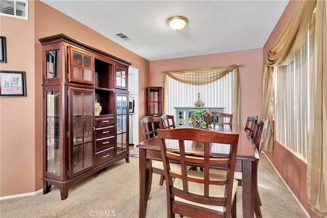 dining space featuring light carpet