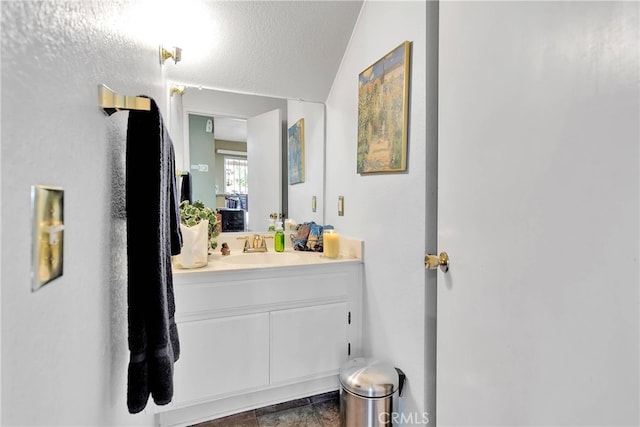 bathroom featuring vaulted ceiling, a textured ceiling, and vanity