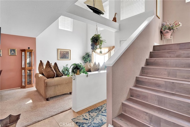 staircase featuring a towering ceiling and tile patterned flooring