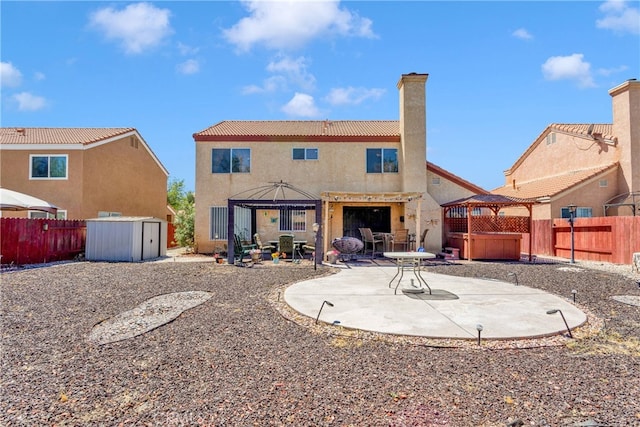 rear view of house featuring a storage unit, a gazebo, a patio area, and a hot tub