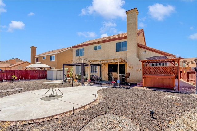 back of property featuring a hot tub and a patio area