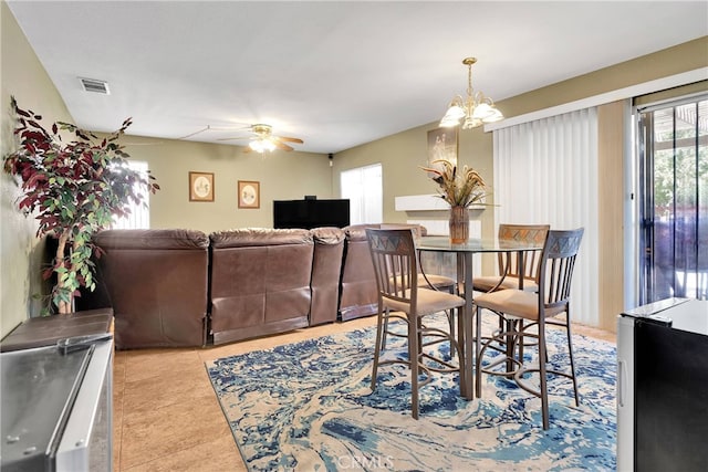 dining space featuring ceiling fan with notable chandelier