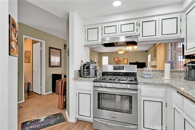 kitchen with white cabinets, light stone counters, stainless steel gas range oven, and light wood-type flooring