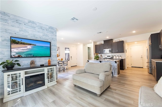 living room featuring wooden walls, light hardwood / wood-style floors, and sink