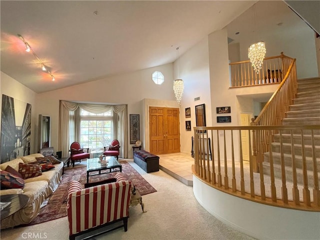 living room featuring a chandelier, light carpet, rail lighting, and high vaulted ceiling