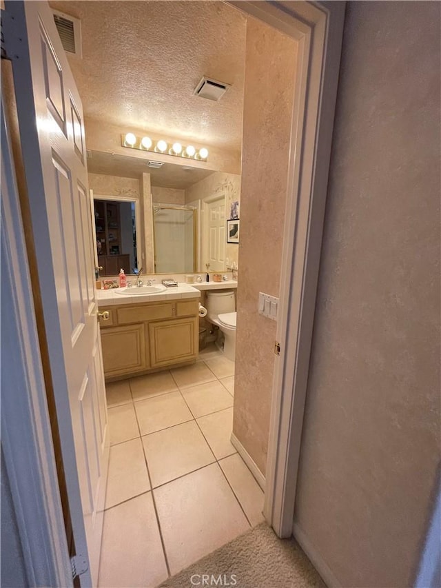 bathroom featuring toilet, vanity, a textured ceiling, and tile patterned floors