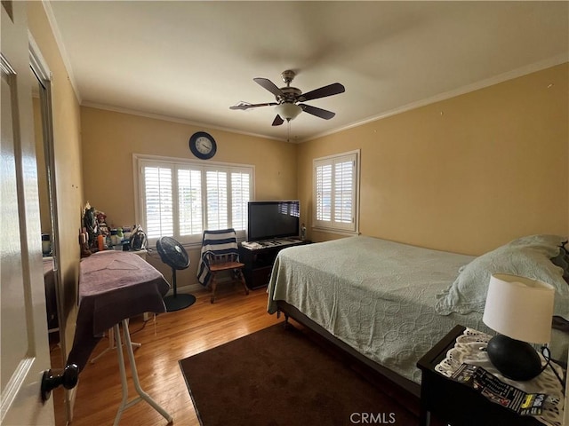 bedroom with hardwood / wood-style floors, ceiling fan, and ornamental molding