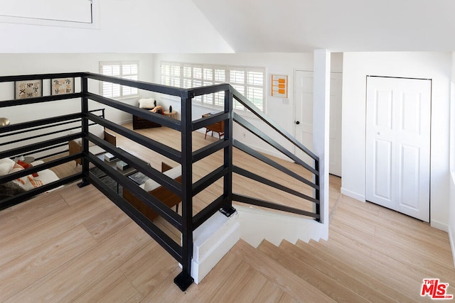 stairway with wood-type flooring and vaulted ceiling