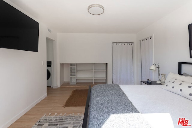 bedroom with washer / clothes dryer and wood-type flooring