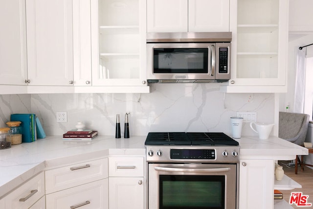 kitchen with white cabinets, stainless steel appliances, and light stone countertops