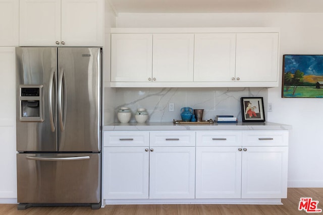 kitchen featuring backsplash, stainless steel fridge, light hardwood / wood-style flooring, and white cabinets