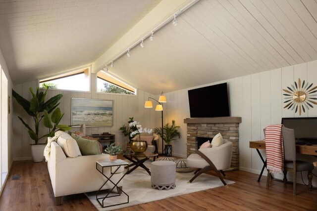 living room with dark wood-type flooring, lofted ceiling with beams, wood walls, track lighting, and a fireplace