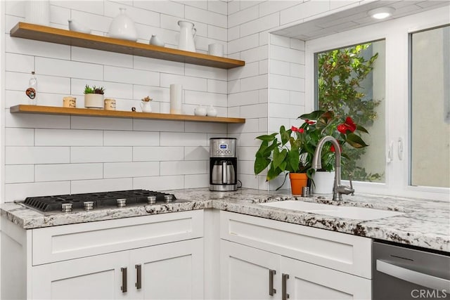 kitchen featuring white cabinets, stainless steel appliances, tasteful backsplash, sink, and light stone counters