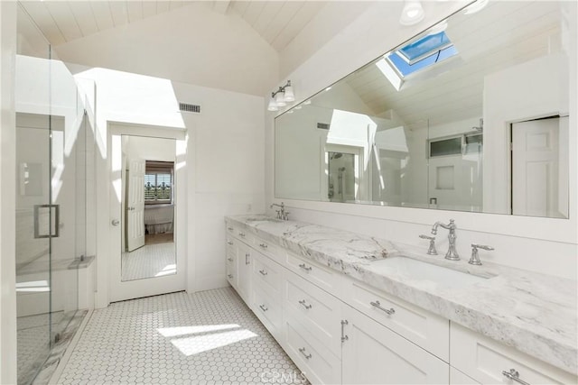 bathroom with vaulted ceiling with skylight, tile patterned flooring, walk in shower, and vanity