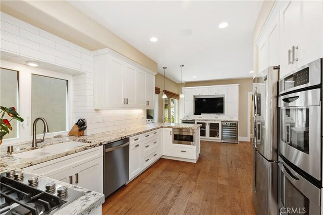 kitchen featuring decorative light fixtures, kitchen peninsula, appliances with stainless steel finishes, and white cabinetry