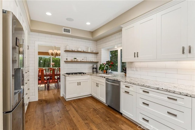 kitchen with decorative backsplash, white cabinetry, and stainless steel appliances