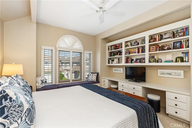 carpeted bedroom with ceiling fan and built in desk