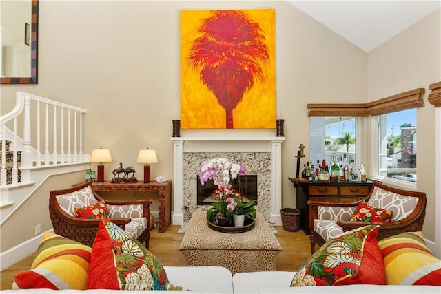 living room featuring a high end fireplace, lofted ceiling, and light hardwood / wood-style flooring