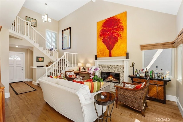 living room featuring a high end fireplace, a towering ceiling, and light hardwood / wood-style floors