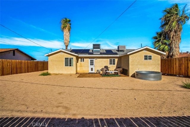 back of property featuring a hot tub, a patio, solar panels, and central air condition unit