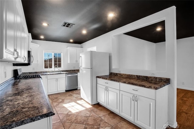 kitchen featuring white cabinets, range, white fridge, and stainless steel dishwasher