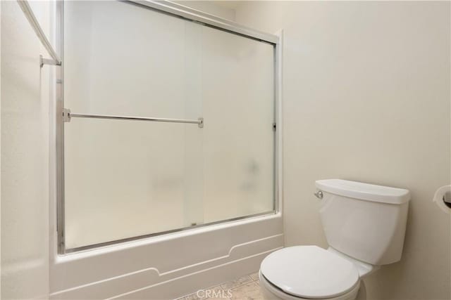 bathroom featuring tile patterned flooring, toilet, and shower / bath combination with glass door