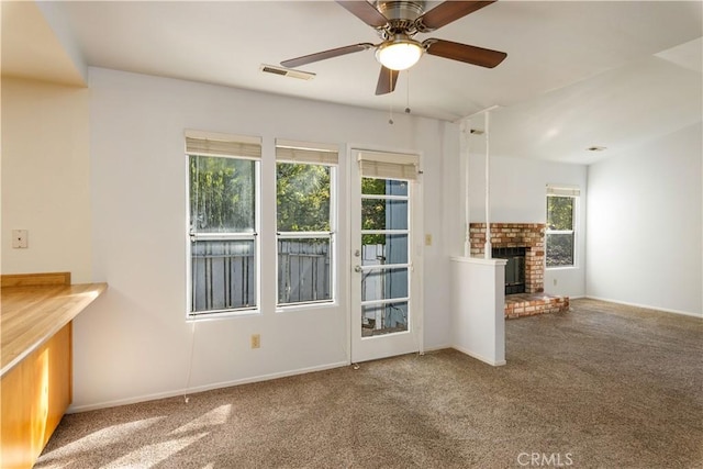 unfurnished living room featuring carpet, a fireplace, and a wealth of natural light