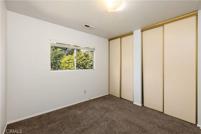 unfurnished bedroom with multiple closets and dark colored carpet