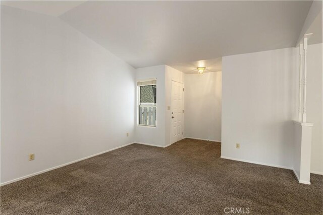 carpeted spare room featuring vaulted ceiling