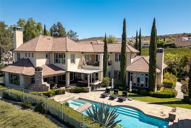 back of house featuring a patio area, a pool with hot tub, and a lawn