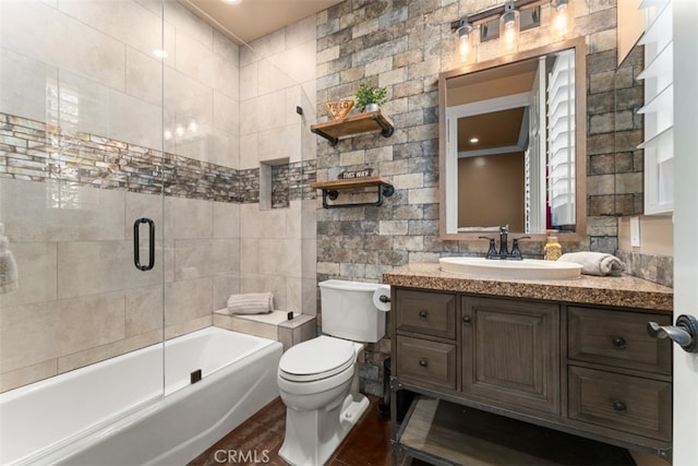 full bathroom featuring vanity, enclosed tub / shower combo, toilet, and tile walls