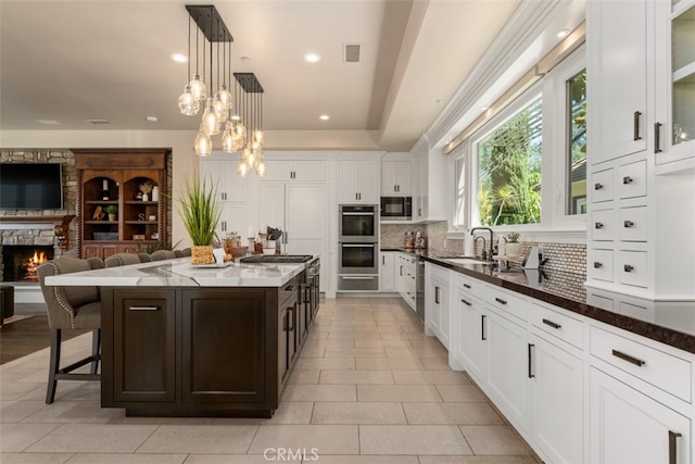 kitchen with decorative backsplash, a kitchen breakfast bar, built in microwave, pendant lighting, and a center island