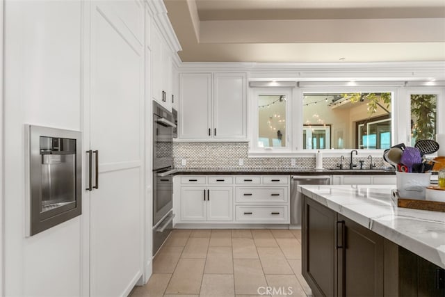 kitchen featuring light stone counters, tasteful backsplash, sink, and white cabinets