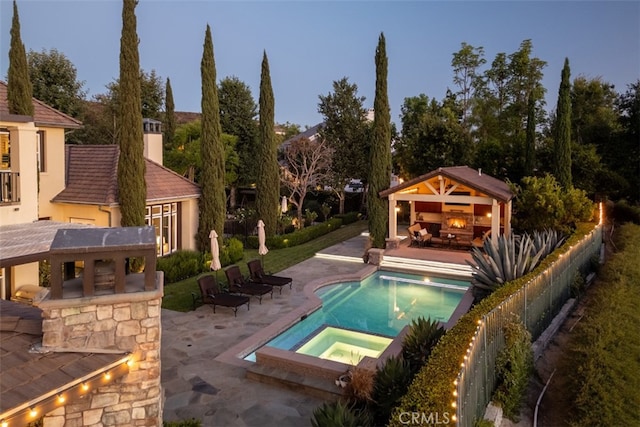 pool at dusk with a gazebo, an in ground hot tub, and a patio area