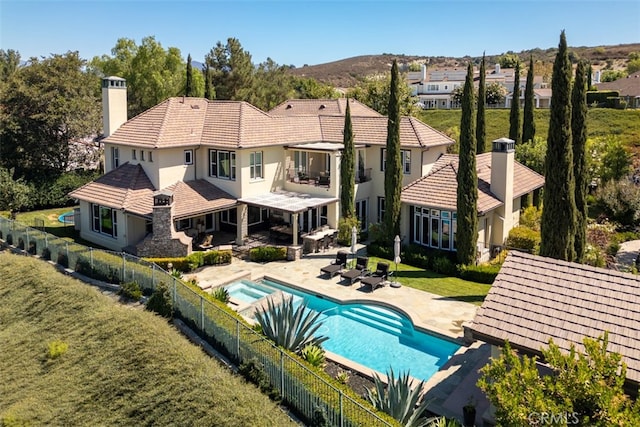 rear view of house featuring a yard, a patio area, and a fenced in pool