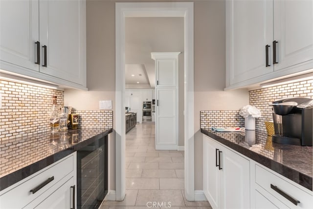 kitchen with wine cooler, white cabinetry, and dark stone countertops