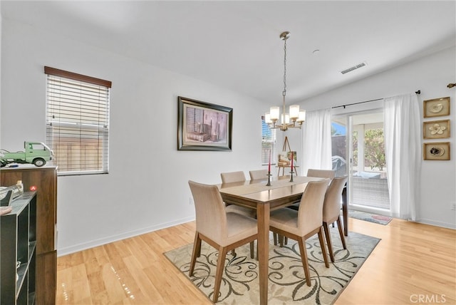 dining room featuring light wood-type flooring, a chandelier, and vaulted ceiling