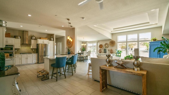 interior space with a tray ceiling, hanging light fixtures, a breakfast bar area, stainless steel appliances, and white cabinets