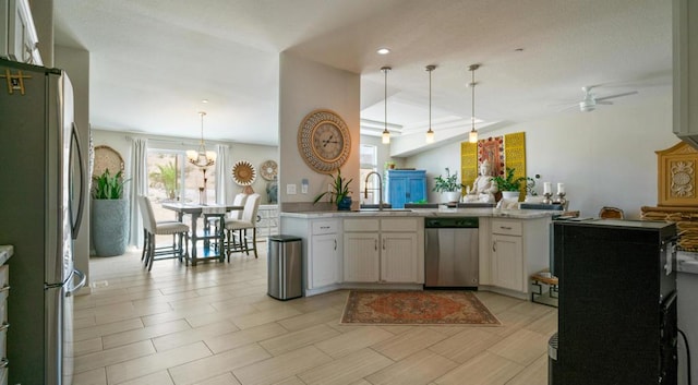 kitchen with appliances with stainless steel finishes, sink, white cabinetry, and decorative light fixtures